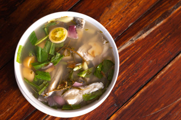 Spicy fish soup flavored with lemongrass and lime served on wooden table