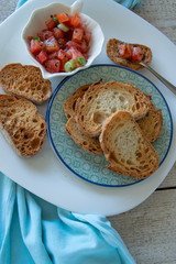 Preparing tasty tomato Italian appetizers -  bruschetta, on slices of toasted baguette, close up view.