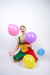 Fototapeta na wymiar funny happy clown girl with colorful air ballons on white studio background