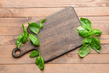 Wooden board with fresh basil on table