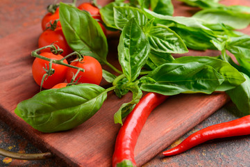 Fresh basil and vegetables on wooden board, closeup