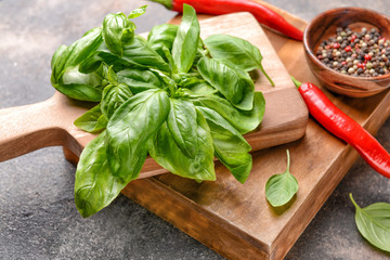 Wooden boards with fresh basil, chili peppers and spices on grey background