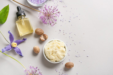 Shea butter with cosmetic products on grey background