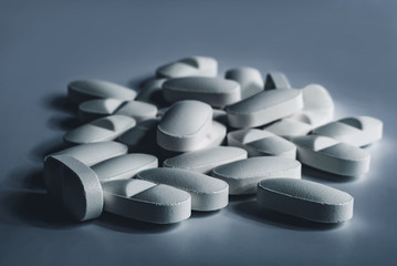 Closeup of many white prescription drugs, medicine tablets or vitamin pills in a pile - Concept of healthcare, opioids addiction, medicament abuse or medication treatment