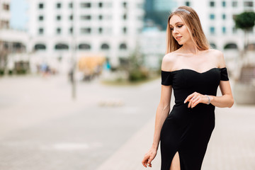 beautiful young girl in black dress walking the streets of the city, the woman is resting outdoors, street fashion. urban lifestyle.