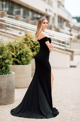 beautiful young girl in black dress walking the streets of the city, the woman is resting outdoors, street fashion. urban lifestyle.