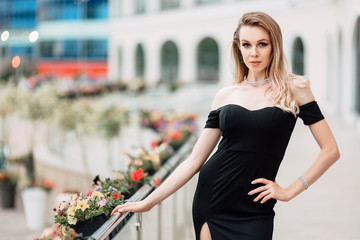 beautiful young girl in black dress walking the streets of the city, the woman is resting outdoors, street fashion. urban lifestyle.