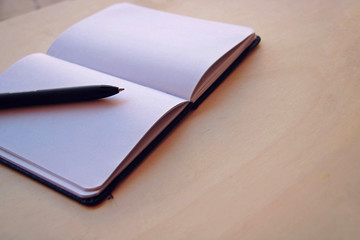 White background with a notebook and a black pen.