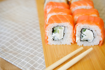 cream rolls with salmon lie on a wooden plank
