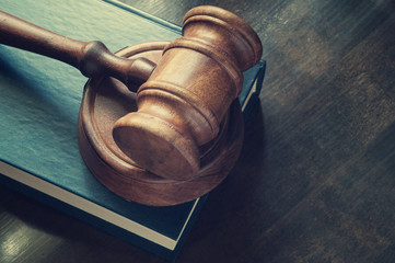 Judge gavel and legal book on wooden table close up