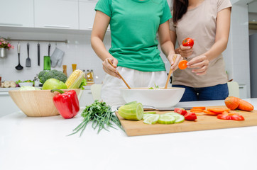Diet. two young pretty woman in green shirt standing and preparing the vegetables salad in bowl for good healthy in modern kitchen at home, healthy lifestyle, cooking, healthy food and dieting concept