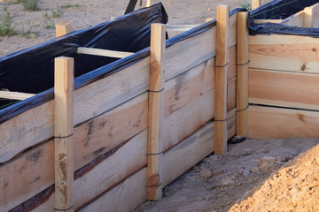 Wooden formwork concrete strip foundation for a cottage. Foundation site of new house, building, details and reinforcements with steel bars and wire rod, preparing for cement pouring