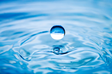 Fototapeta na wymiar The round transparent drop of water, falls downwards. Selective focus.