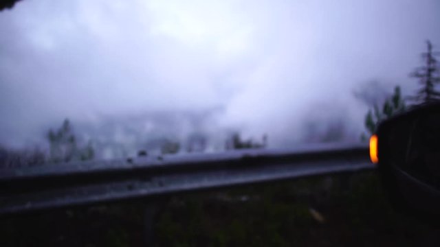 Blur view of rainy foggy picturesque roas and forest from car glass stopped on the roadside. Close-up. Foggy road. Cyprus.