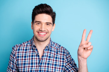 Naklejka premium Portrait of cute pretty classy man youngster isolated have free time rest rejoice relax make v-signs dressed checkered modern outfit on blue background