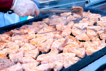 Fish steaks on a large baking sheet puts a hand in a white glove. Cooking fish, meat in the open air for guests. Food in hotels on vacation in Turkey.