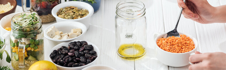 cropped view of woman adding couscous in jar with oil, panoramic shot
