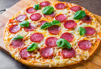 Pepperoni Pizza with Mozzarella cheese, salami, Tomato sauce, pepper, Spices and Fresh basil. Italian pizza on wooden table background