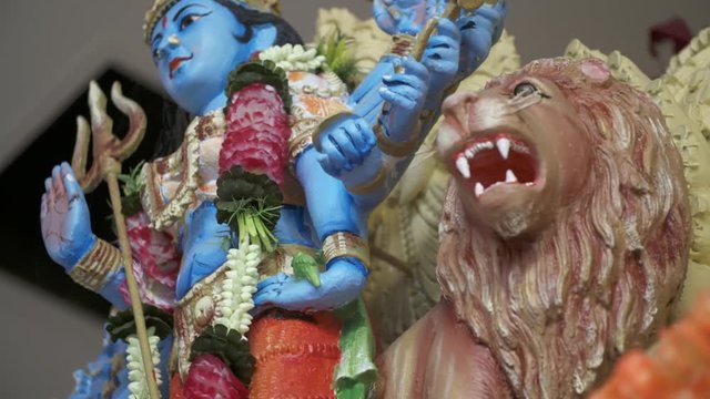 Handheld, close up shot of small sculptures of Vishnu and a roaring lion.