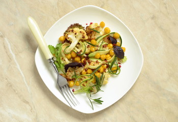 Roasted cauliflower with chickpeas, zucchini noodles and rosemary, salad, top view, copy space