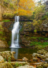 Fototapeta na wymiar beautiful cascade waterfall in autumn forest, silky smooth stream - Image