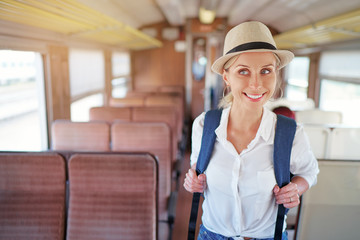 Enjoying trip. Young pretty woman with rucksack traveling by the train.