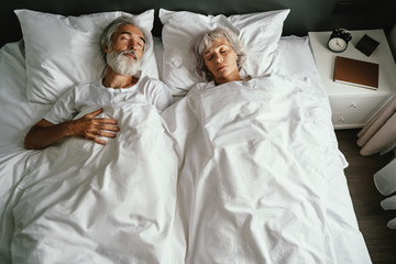 Senior family couple sleeping together in bed.