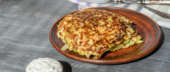 Vegetarian cuisine - Vegetable pancakes from cabbage and zucchini and white sauce with parsley and garlic