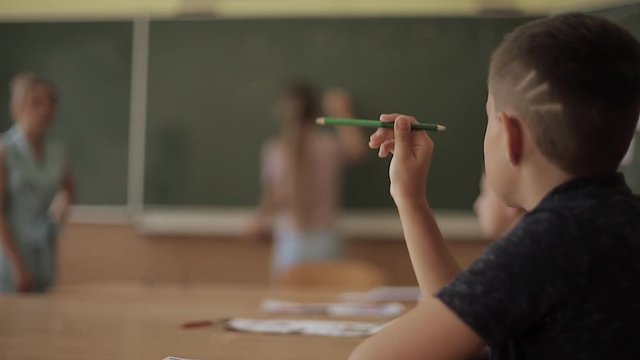 Schoolboy rise hand in classroom. Elementary school. Education