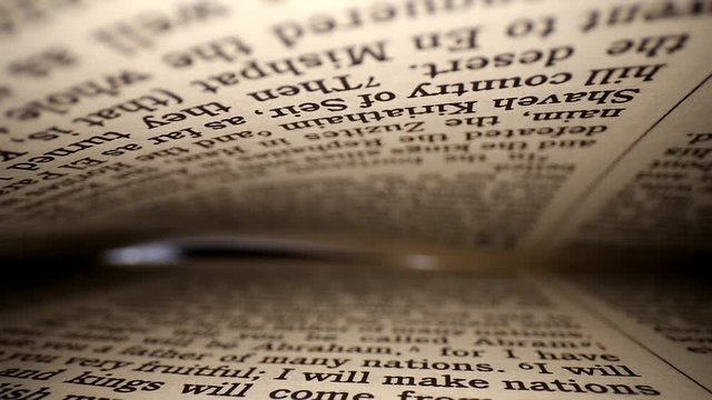 Pulling a lens out of a book diagonally. Words eye view of the pages; Shallow focus. The page @end is lit by soft warm light which narrows as the pages close.