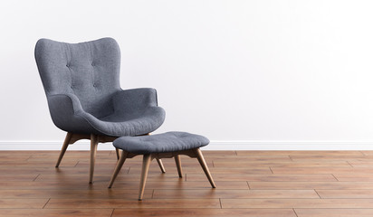 Fashionable modern gray armchair with wooden legs, ottoman against a white wall in the interior....