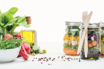 fresh vegetable salad in glass jars with wooden cutlery isolated on white