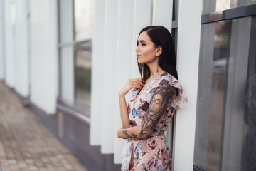 Beautiful young woman in colored dress posing near business center