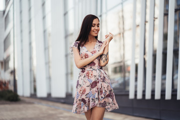 Beautiful happy young woman in colored dress posing near business center