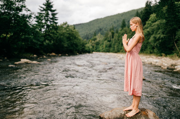 Young girl praying at nature, eyes closed.