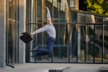 Crazy young businessman dancing on the street with bag. Celebrating victory. Flexibility and grace...