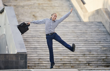 Crazy young businessman dancing on the street with bag. Celebrating victory. Flexibility and grace...
