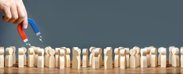 hand with a magnet is combing through a crowd. Search for suitable people for work, patients for...