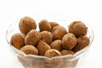 Pile of fresh new raw potatoes with peel on in a glass bowl. Close up on white background. - Image