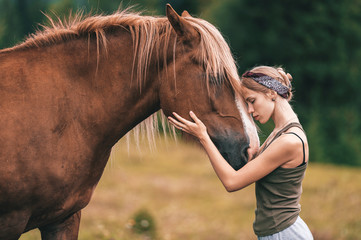 Young beautiful girl hugging horse at nature. Horse lover.