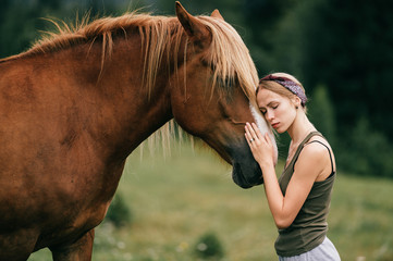 Young beautiful girl hugging horse at nature. Horse lover.