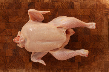 Raw chicken on a chopping board ready to be prepared for cooking. Top view image on wooden background.
