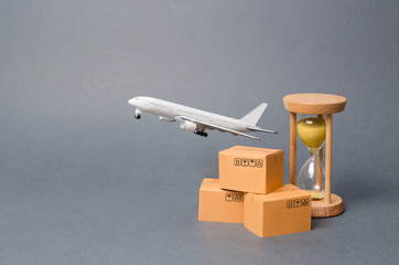 Airplane takes off behind the stack of cardboard boxes and a sand clock. concept of air cargo and...
