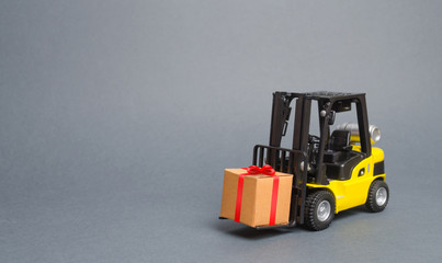 Yellow forklift truck carries a gift with a red bow. Purchase and delivery of a present. retail, discounts and contests. sweepstakes and contest promotions. Increase sales and attract new customers.