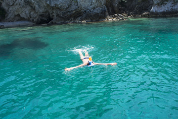 Young woman snorkeling with mask in clear blue water of the sea or ocean