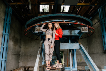 Stylish female couple posing at abandoned cableway station
