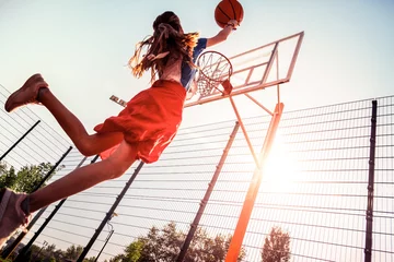 Fotobehang Dark-haired tall teenage girl with basketball skills throwing ball © Viacheslav Yakobchuk