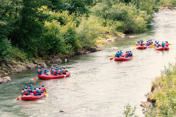 Fototapeta na wymiar A group of men and women rafting on the river. Extreme water sport.