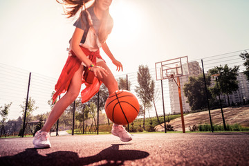 Experienced dark-haired young girl running around basketball playground