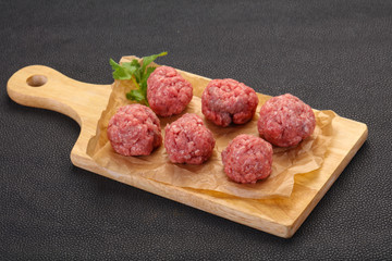 Raw meatball over wooden background